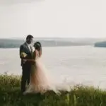 Bride and groom by the water on their wedding day – ideal setting for large wedding party transportation planning